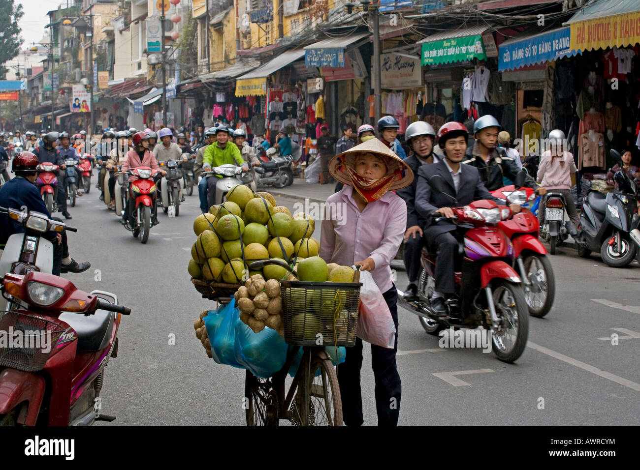 A mobile fruit and vegetable merchant and a crowd of motorcyclists on the busy streets of HANOI VIETNAM Stock Photo