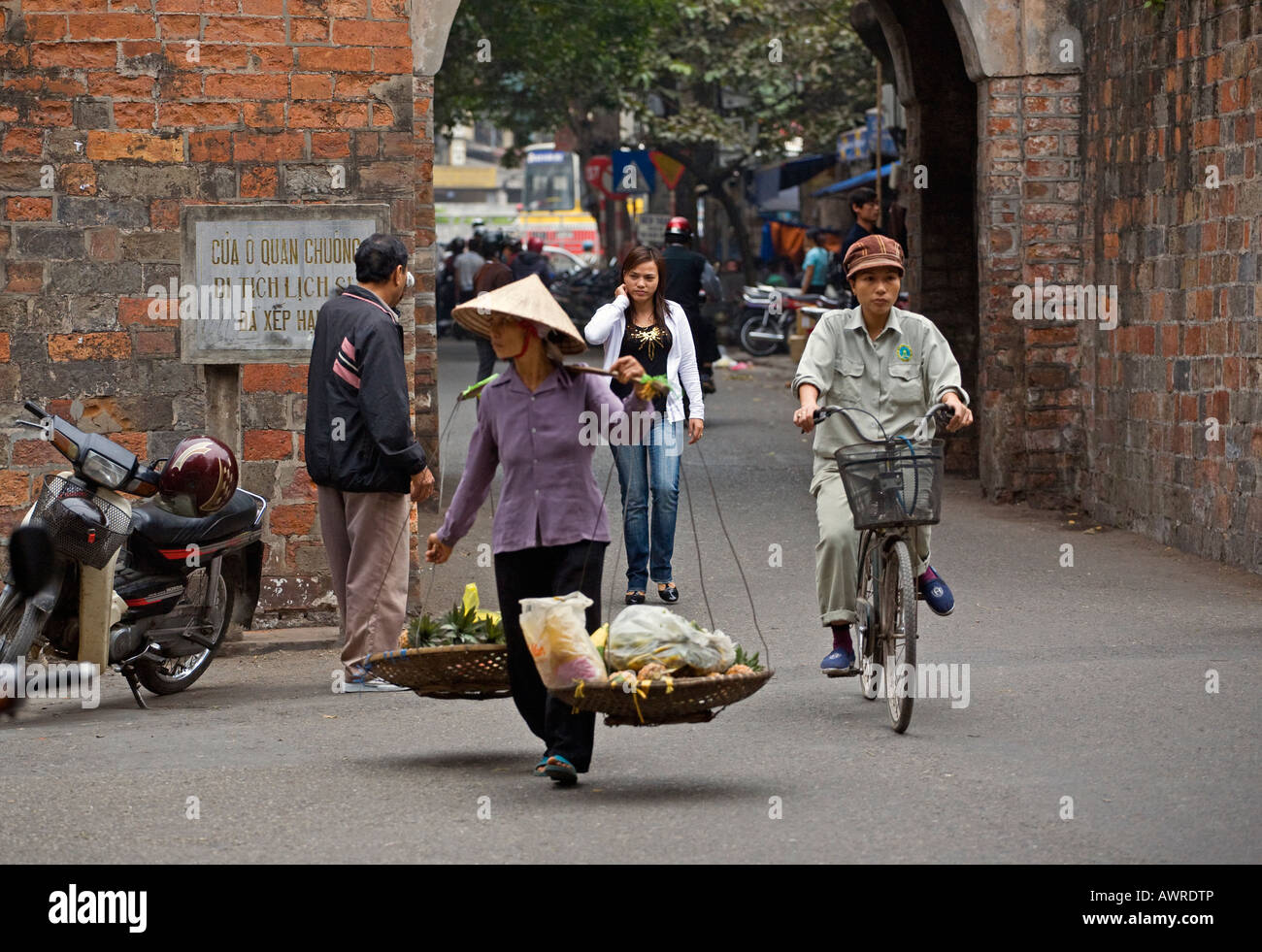 A STREET MERCHANT exits the OLD CITY GATE gate in the city of HANOI VIETNAM Stock Photo
