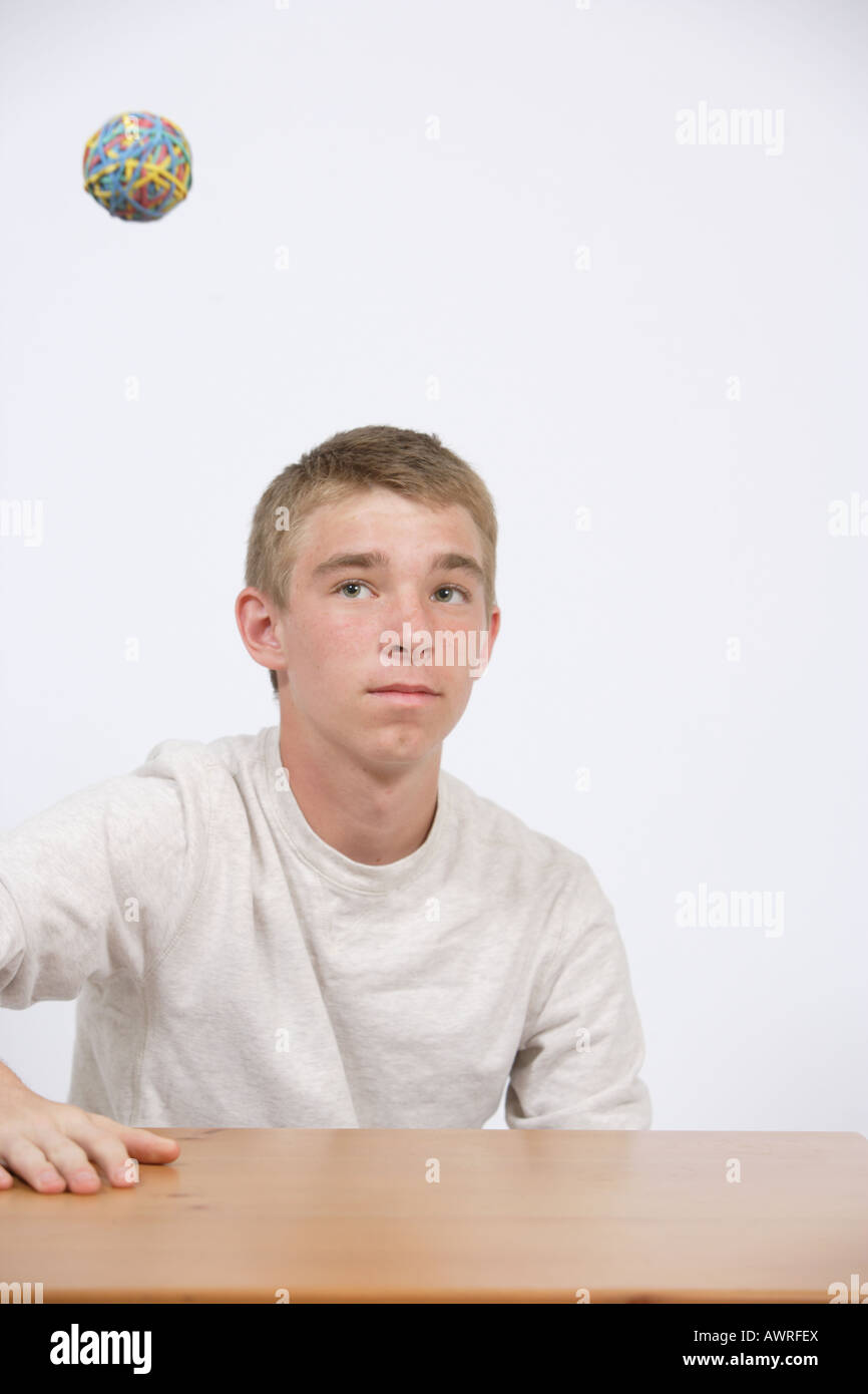 A teen age student playing with a rubber band ball in class Stock Photo