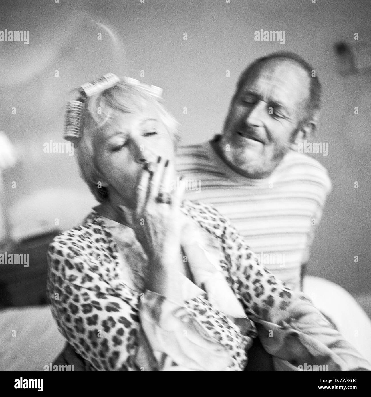 Mature couple sitting, woman smoking cigarette, b&w Stock Photo