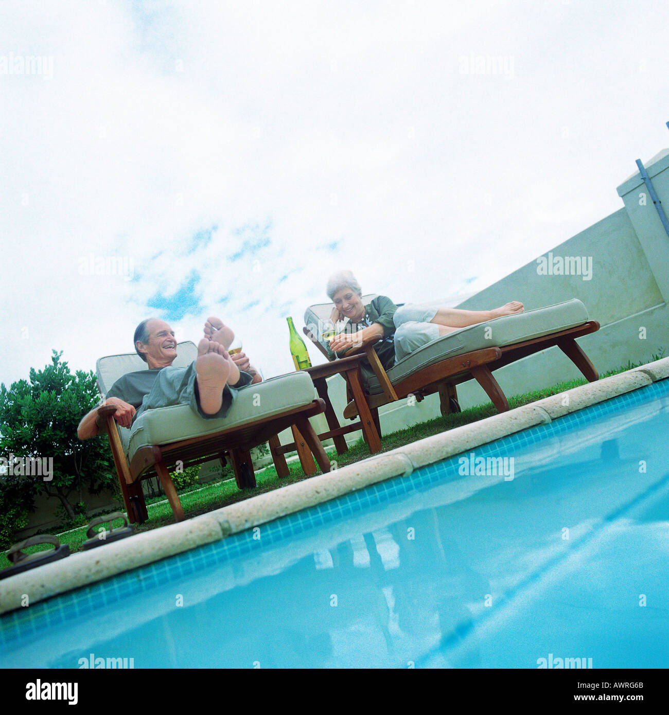 Mature couple lying in lounge chairs beside swimming pool Stock Photo Alamy