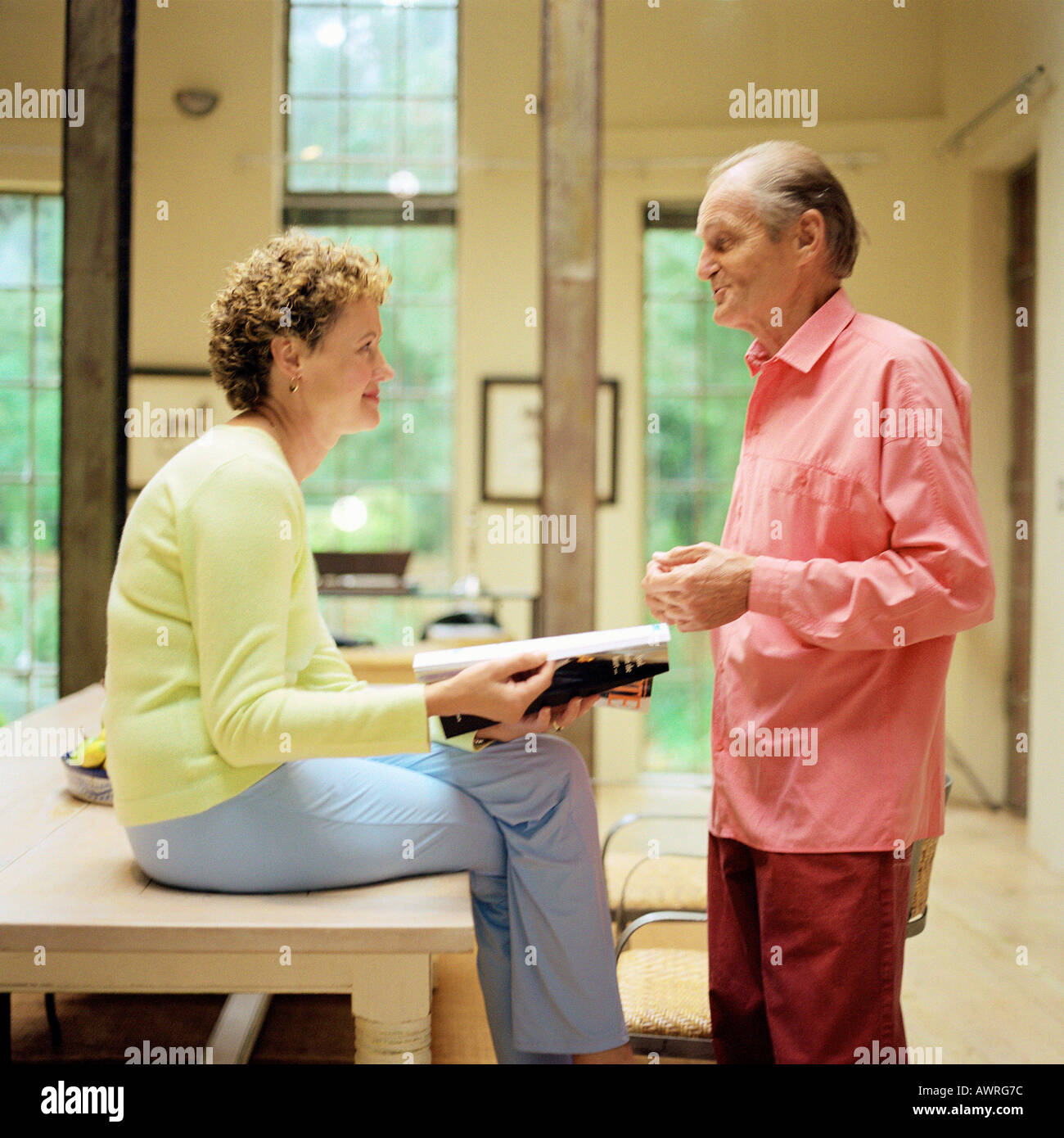 Mature couple face to face, woman sitting on table, man standing, side view  Stock Photo - Alamy