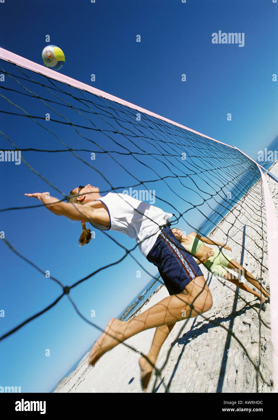 Two young women playing beach volleyball, one in midair Stock Photo