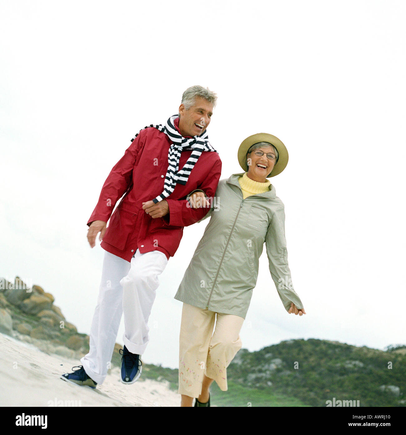 Mature couple walking arm in arm on beach Stock Photo Alamy