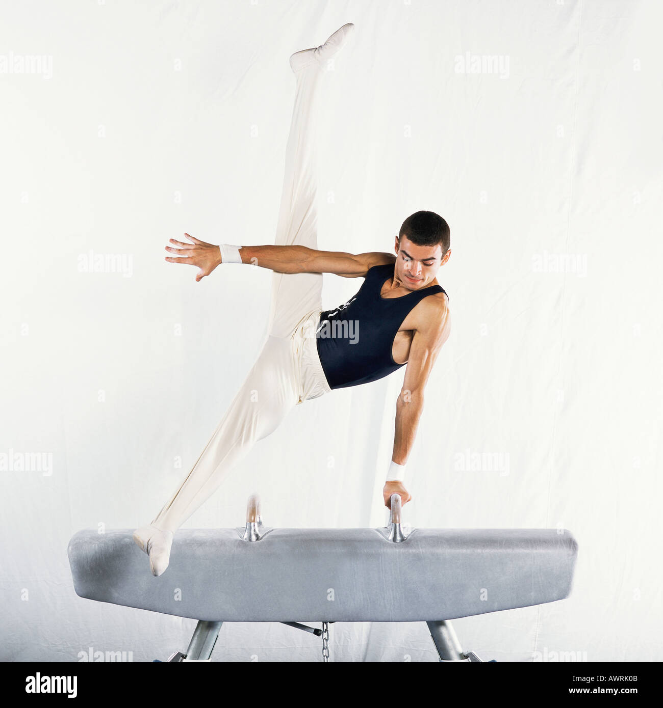 Young male gymnast performing scissors routine on pommel horse Stock