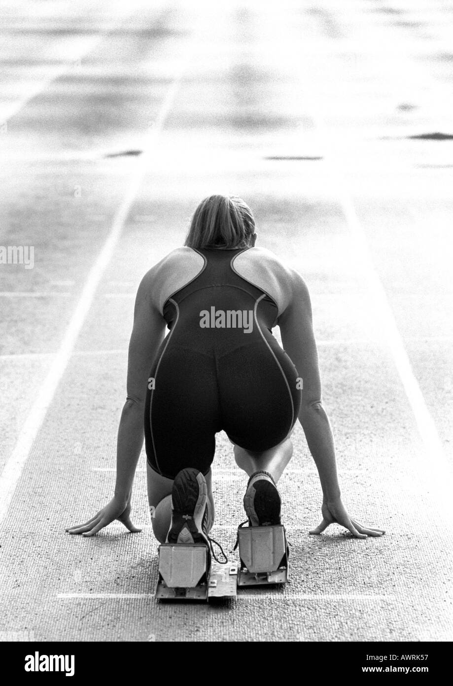 Female runner at starting block, rear view, b&w Stock Photo