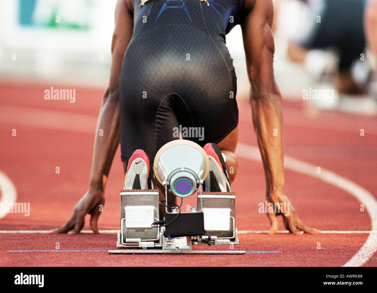 Male runner on starting block, rear view Stock Photo