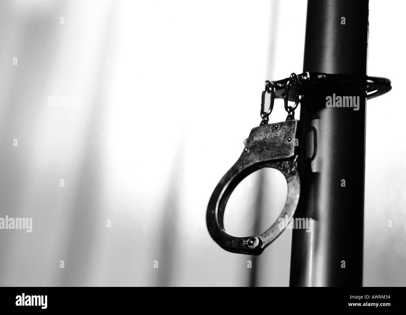 Handcuffs attached to pipe, b&w. Stock Photo
