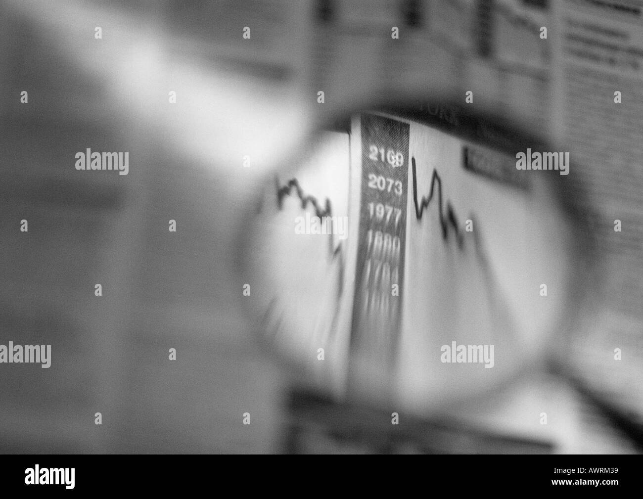Stock and share graphs seen through magnifying glass, b&w. Stock Photo