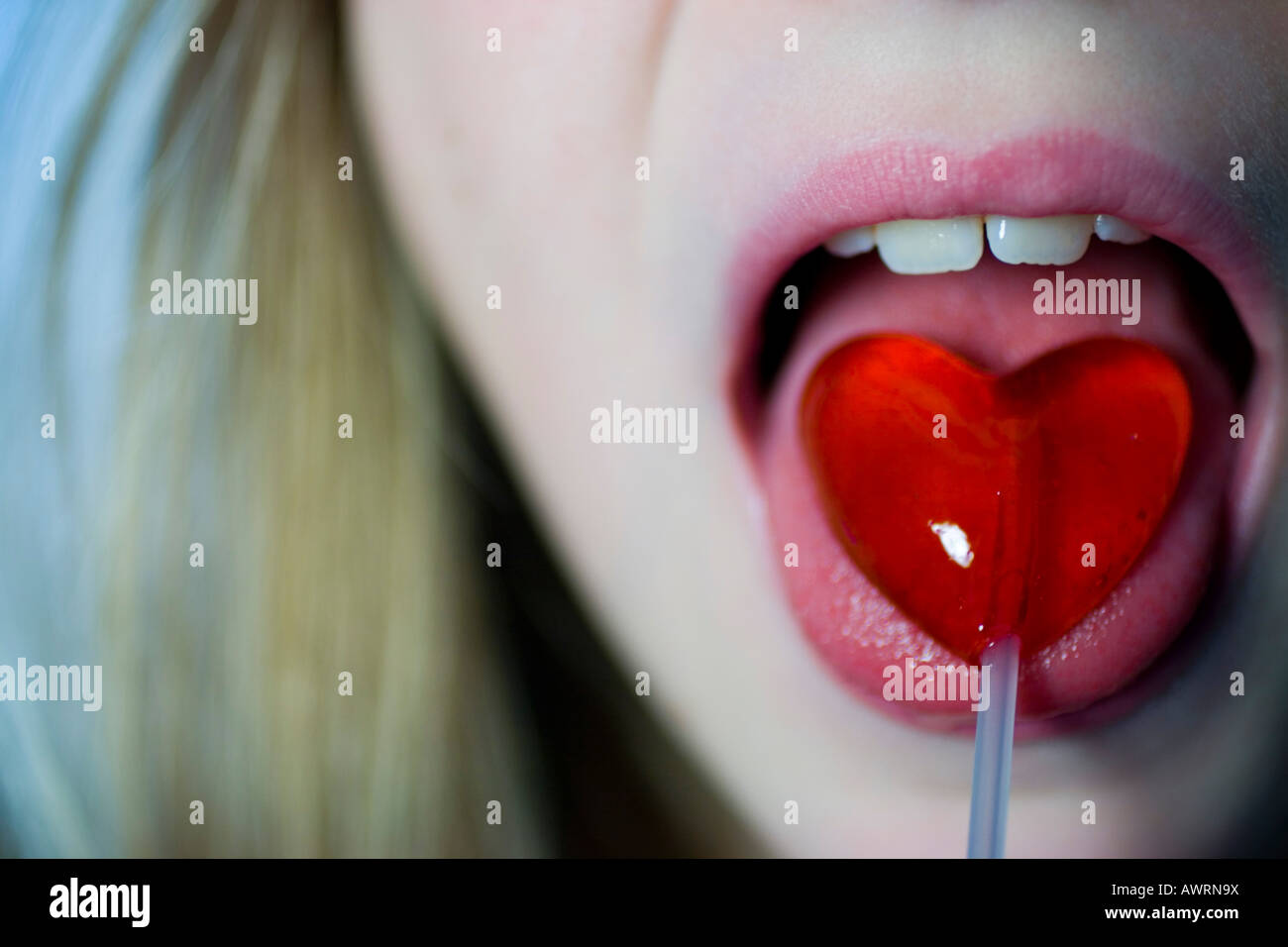 Young girl licking a heart shaped lollipop Stock Photo