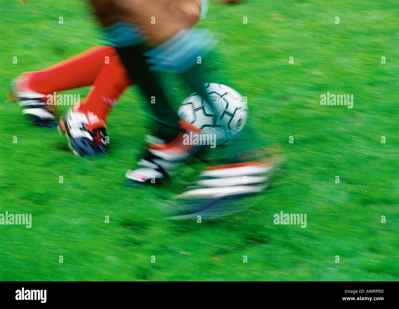 Two soccer players running for ball, low section, blurred. Stock Photo