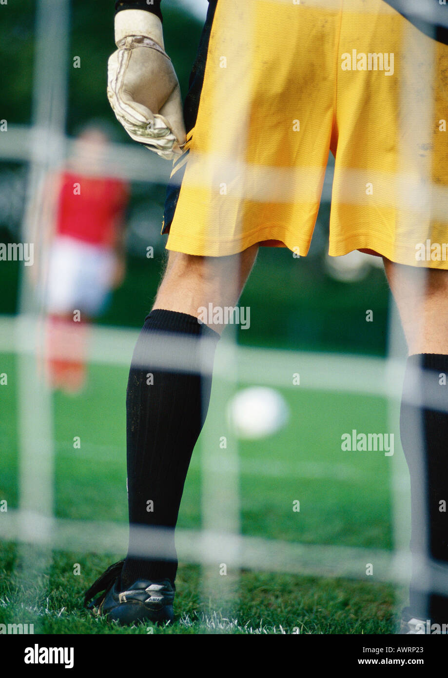 Goal keeper defending goal area when opponent is about to take penalty kick, seen from behind the goal. Stock Photo