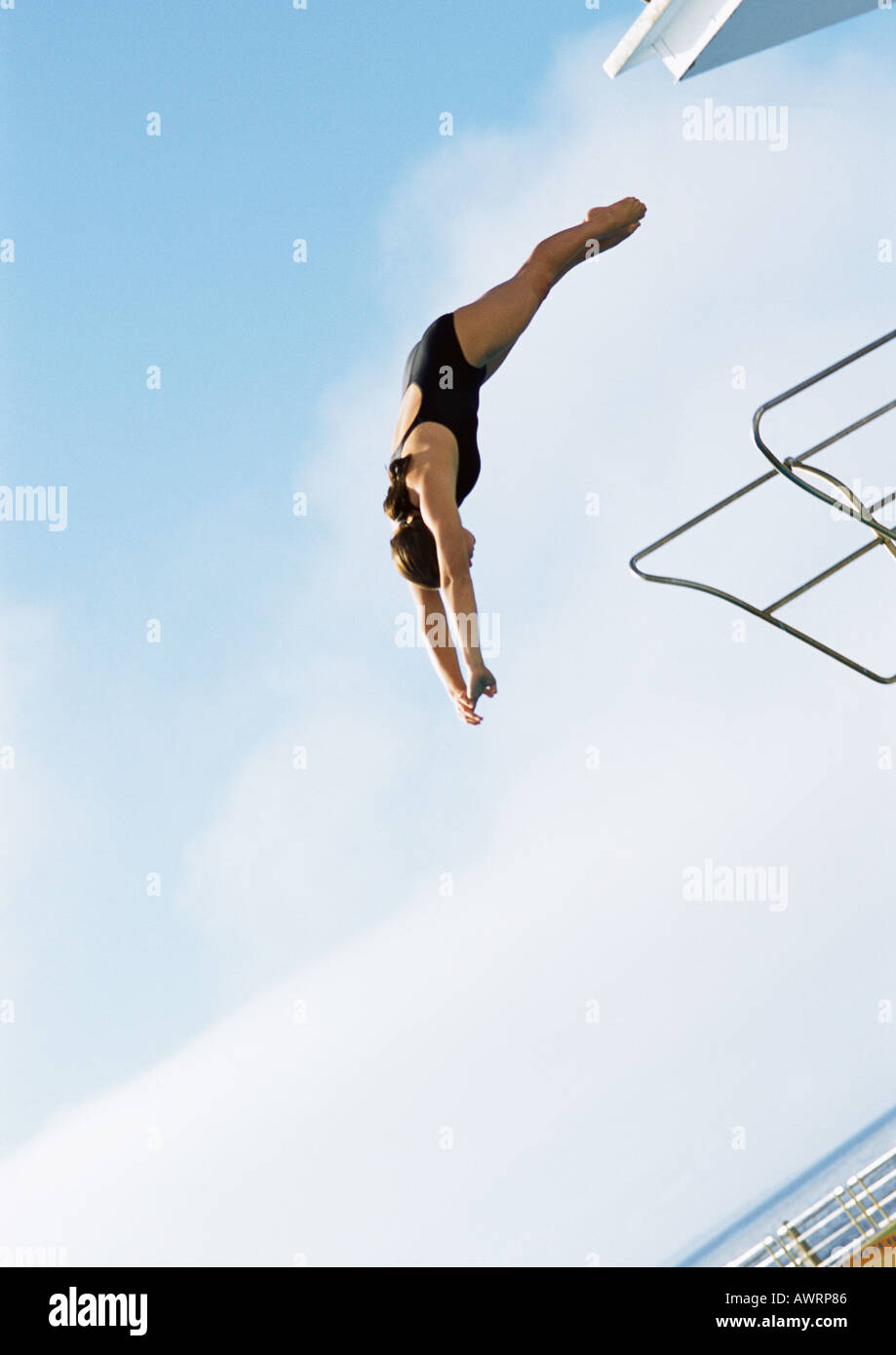 Woman in mid-dive, low angle view, full length, blue sky in background Stock Photo