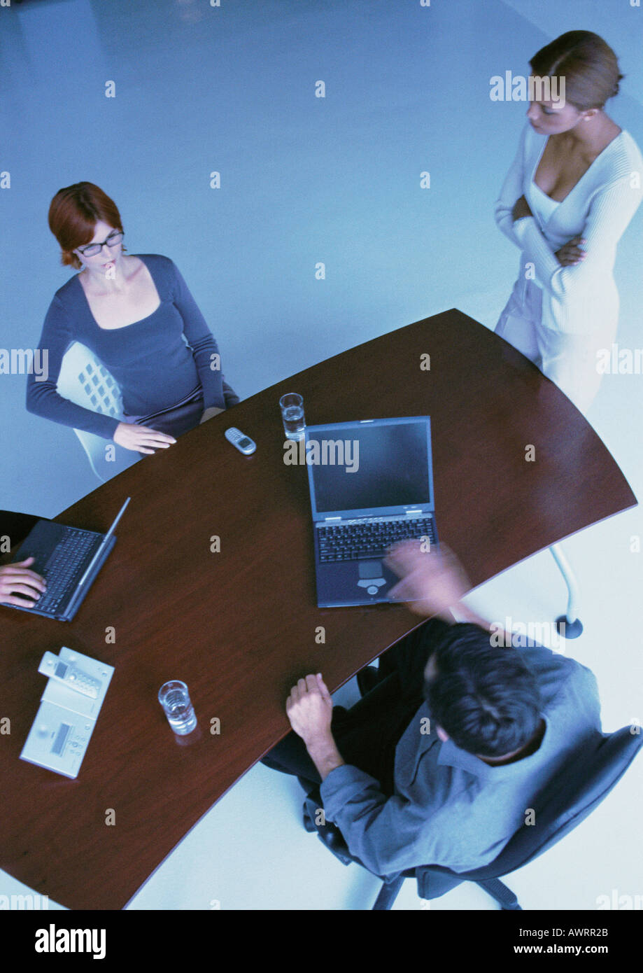 Business people around desk, two with laptops, elevated view Stock Photo