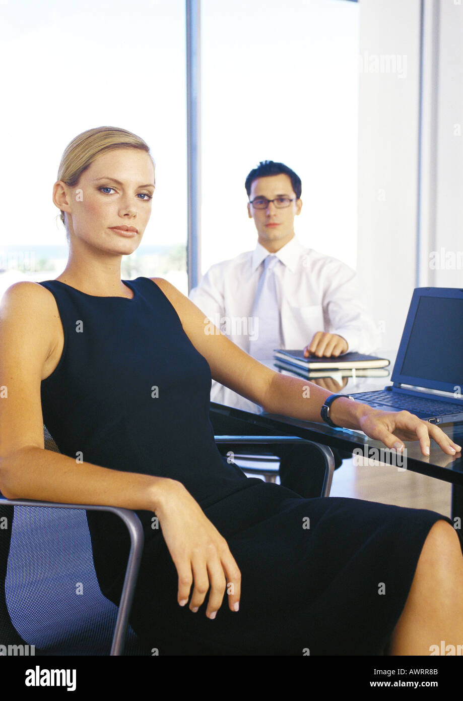 Businessman and woman sitting in office, portrait Stock Photo