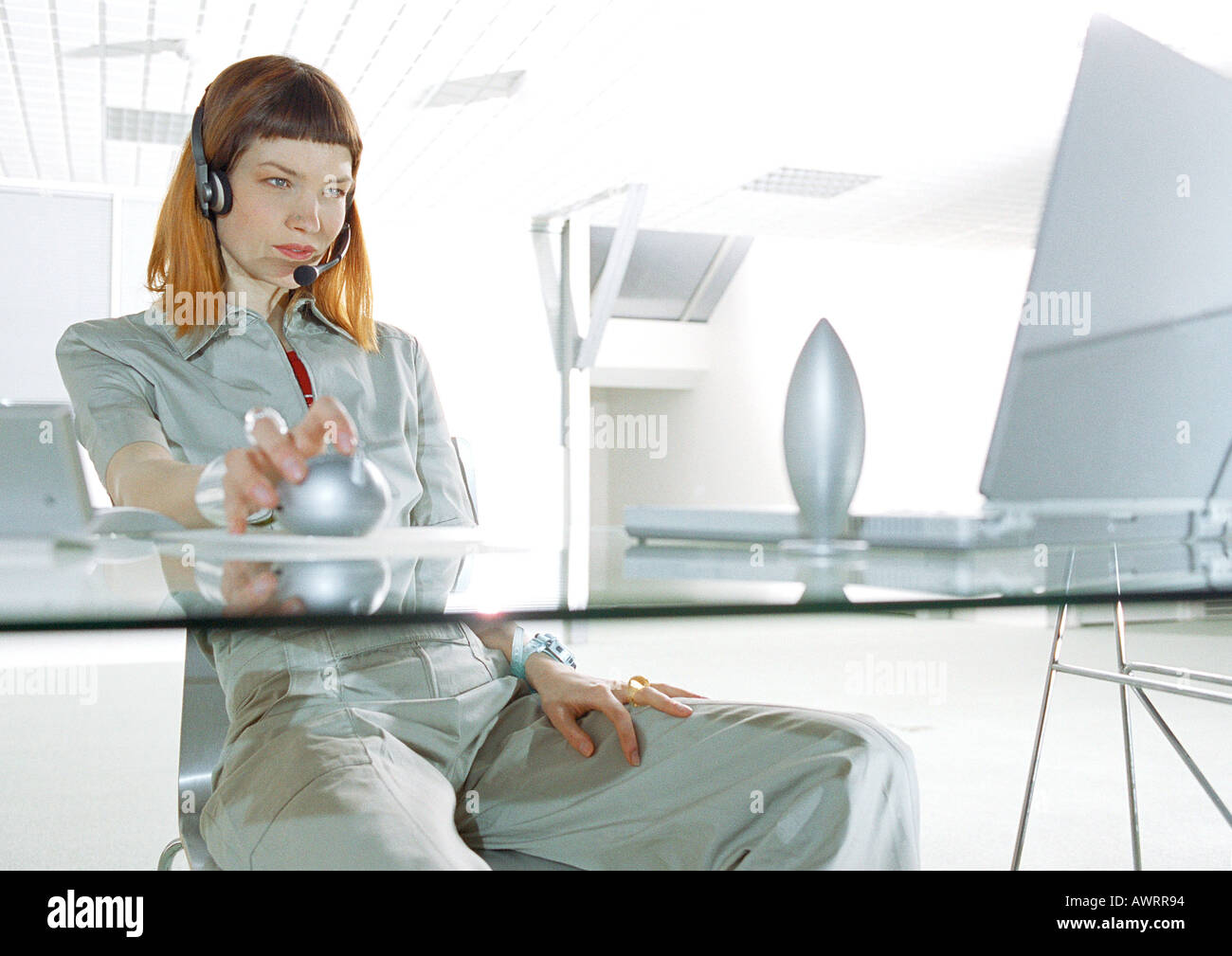 Woman wearing headset, sitting at desk, three quarter length Stock Photo