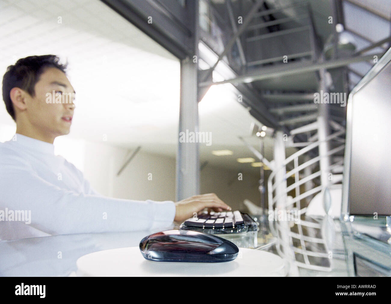 Man working on computer, side view, focus on mouse in foreground Stock Photo
