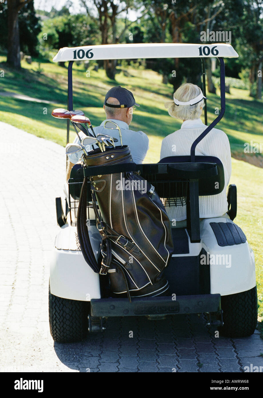 Mature man and woman in golf cart, rear view Stock Photo