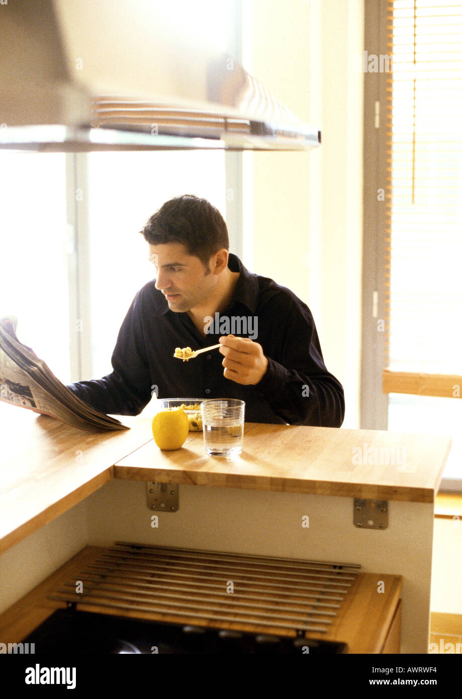 Man eating and reading newspaper Stock Photo