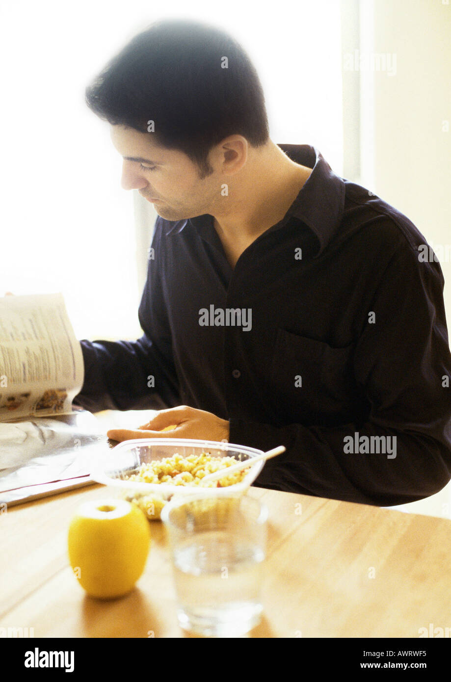 Man reading and eating Stock Photo