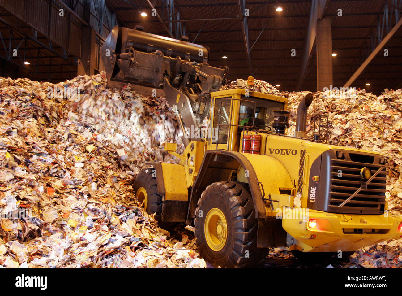 Bulldozer heaping waste paper to be recycled for paper production at ...