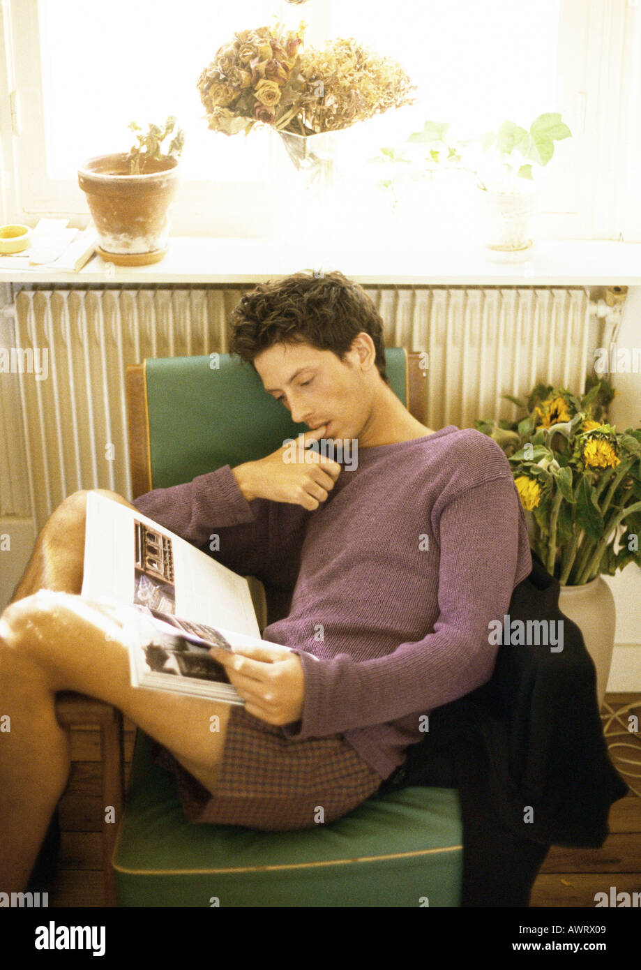 Man sitting in armchair, reading Stock Photo