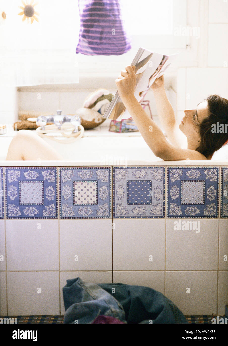 Woman reading in bathtub, side view Stock Photo