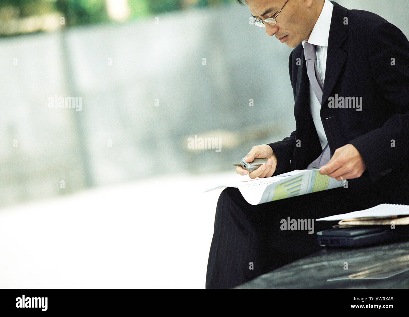 Businessman sitting outdoors, examining documents Stock Photo