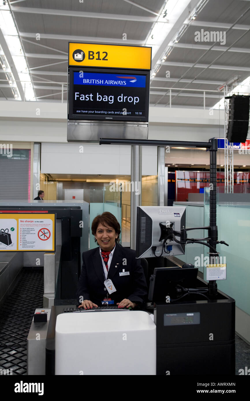 A British Airways Check in Staff person manning a fast bag drop desk at London Heathrow Airport terminal 5 Stock Photo