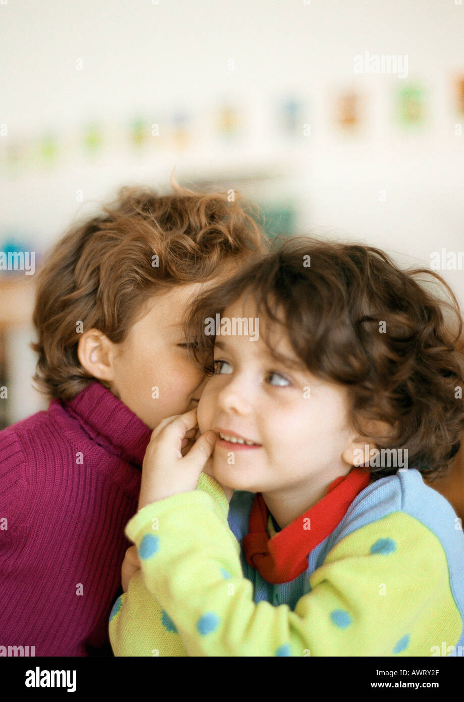 Two children, one whispering to the other Stock Photo - Alamy