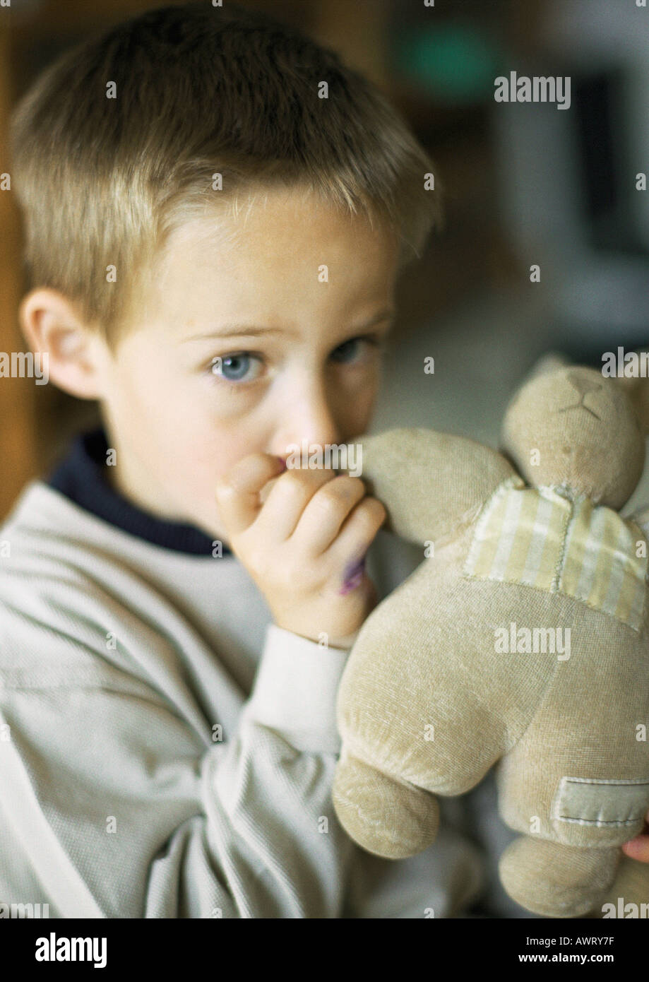 Child with thumb in mouth holding stuffed animal, portrait Stock Photo