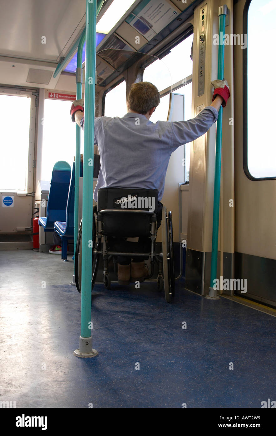 Man on wheelchair travelling alone on a Dockland Light Railway train London UK Stock Photo