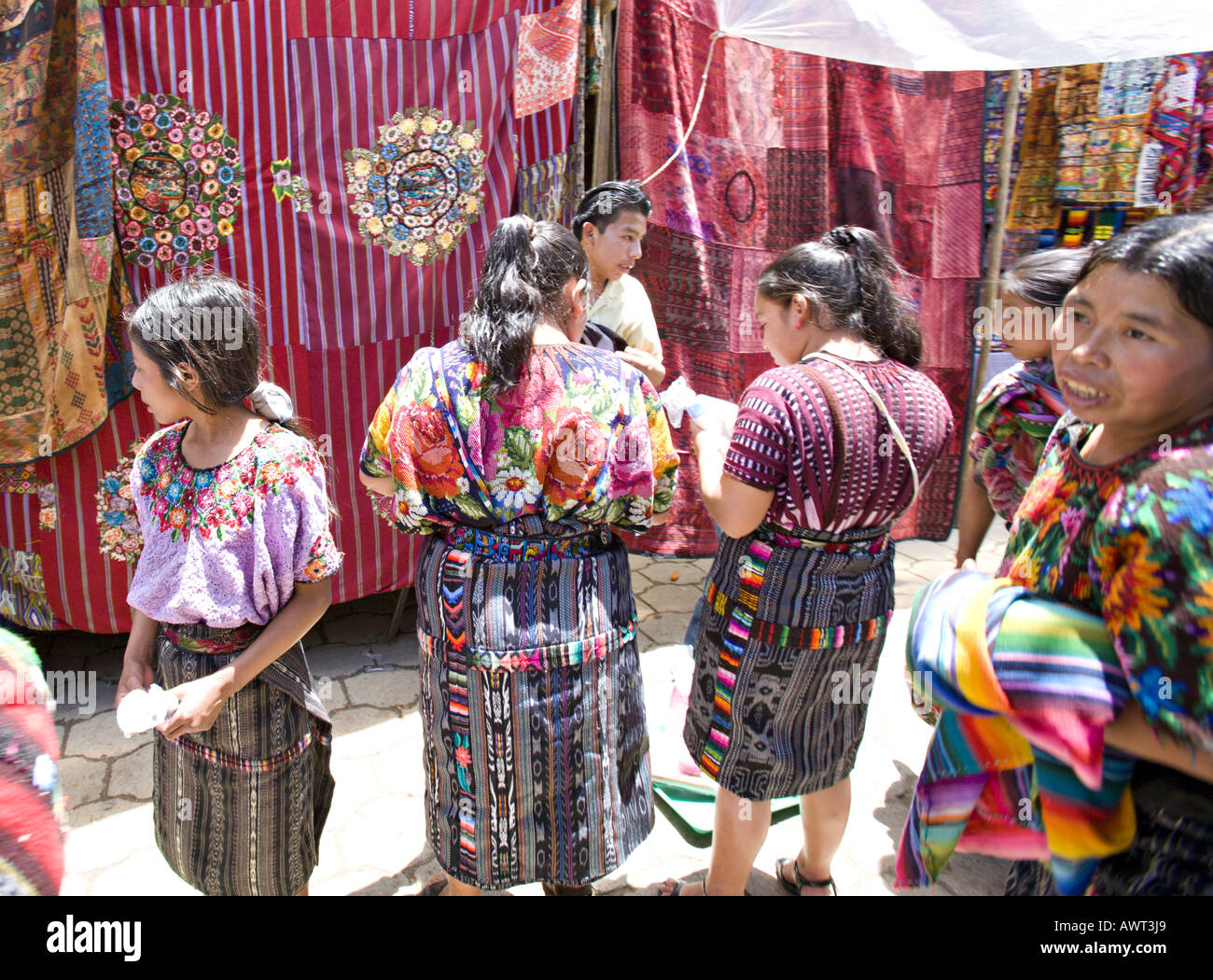 GUATEMALA CHICHICASTENANGO Quiche Mayan women in colorful traditional dress stand in front of the handwoven textiles for sale Stock Photo Alamy