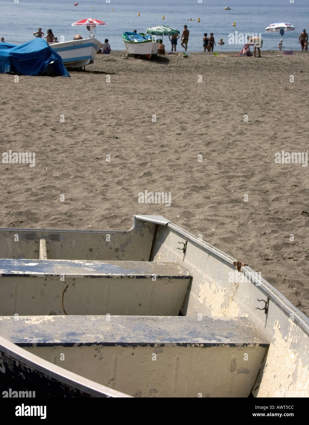 Wooden Fishing Boats on Beach with Parasols and Sunbathers Stock Photo