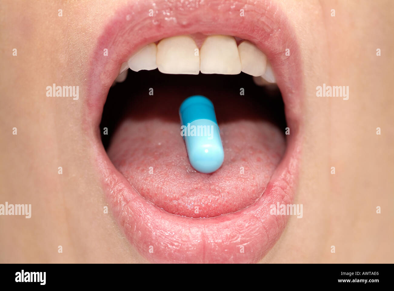 Females Mouth with a Capsule on the Tongue, Close Up. Stock Photo