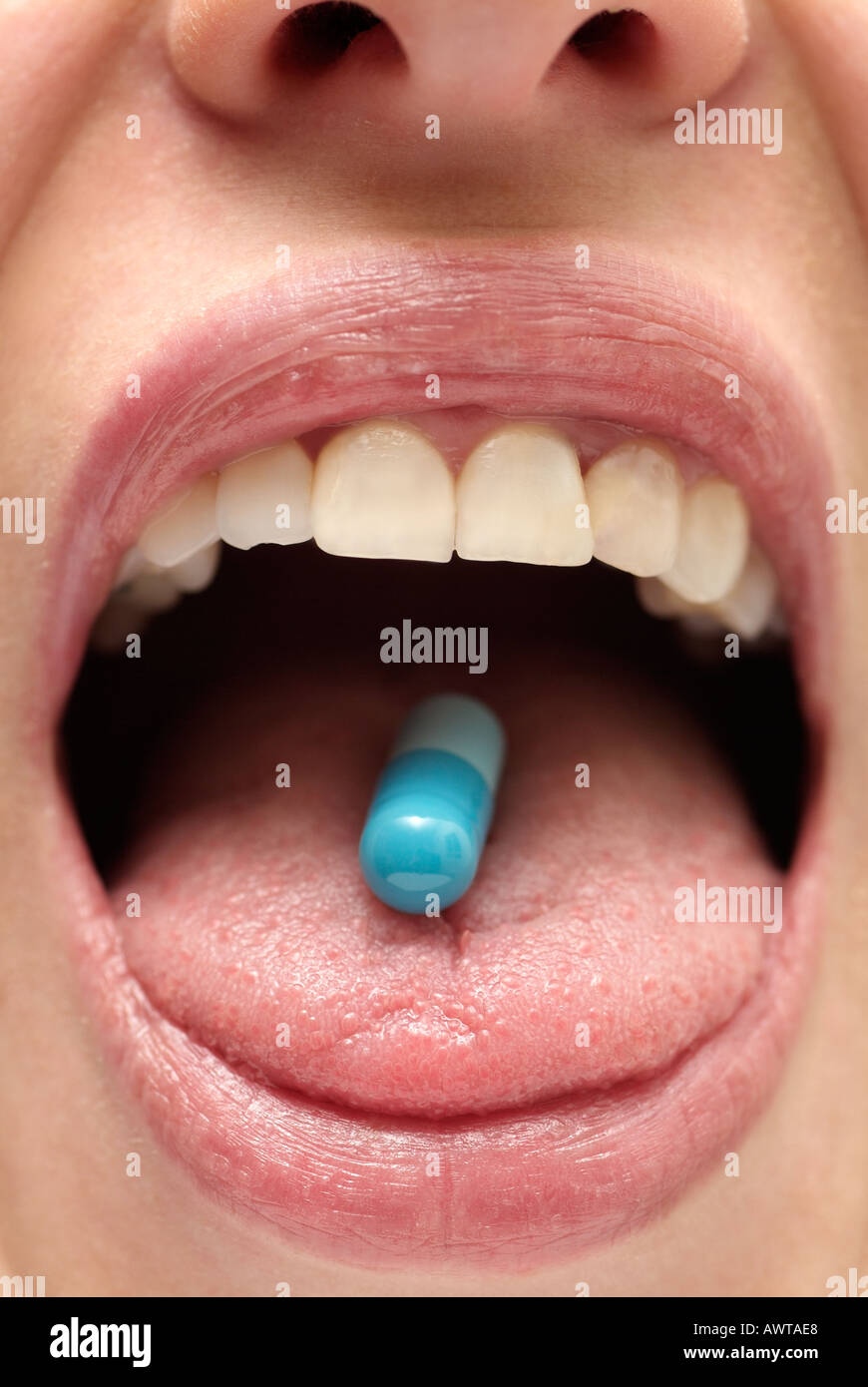 Females Mouth with a Capsule on the Tongue, Close Up. Stock Photo