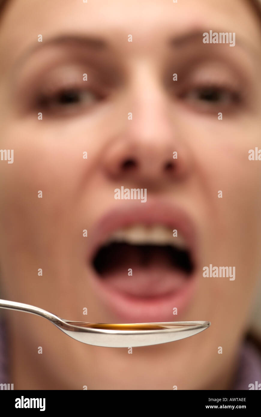 Young Woman Taking a Spoonful of Medicine Stock Photo