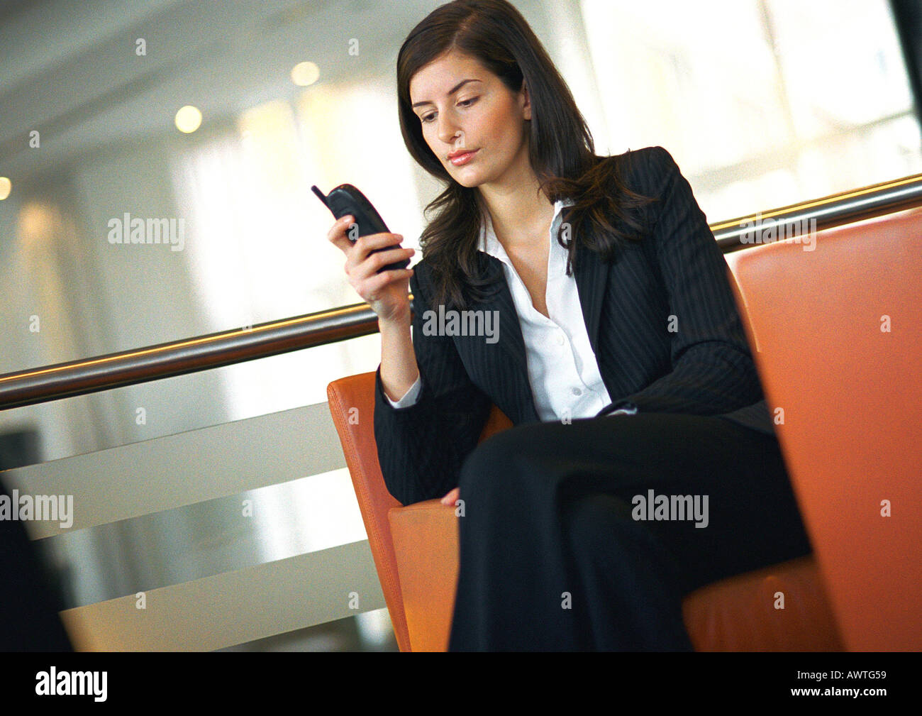 Businesswoman sitting, using cell phone Stock Photo
