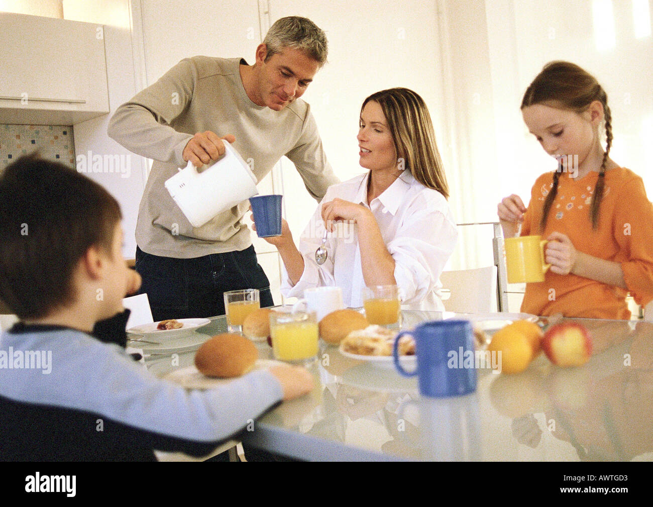 Family eating breakfast together, father pouring drinks Stock Photo