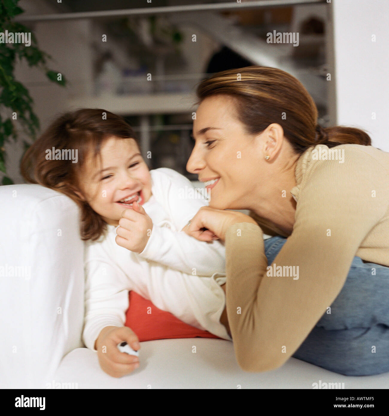 Woman tickling daughter on couch Stock Photo - Alamy