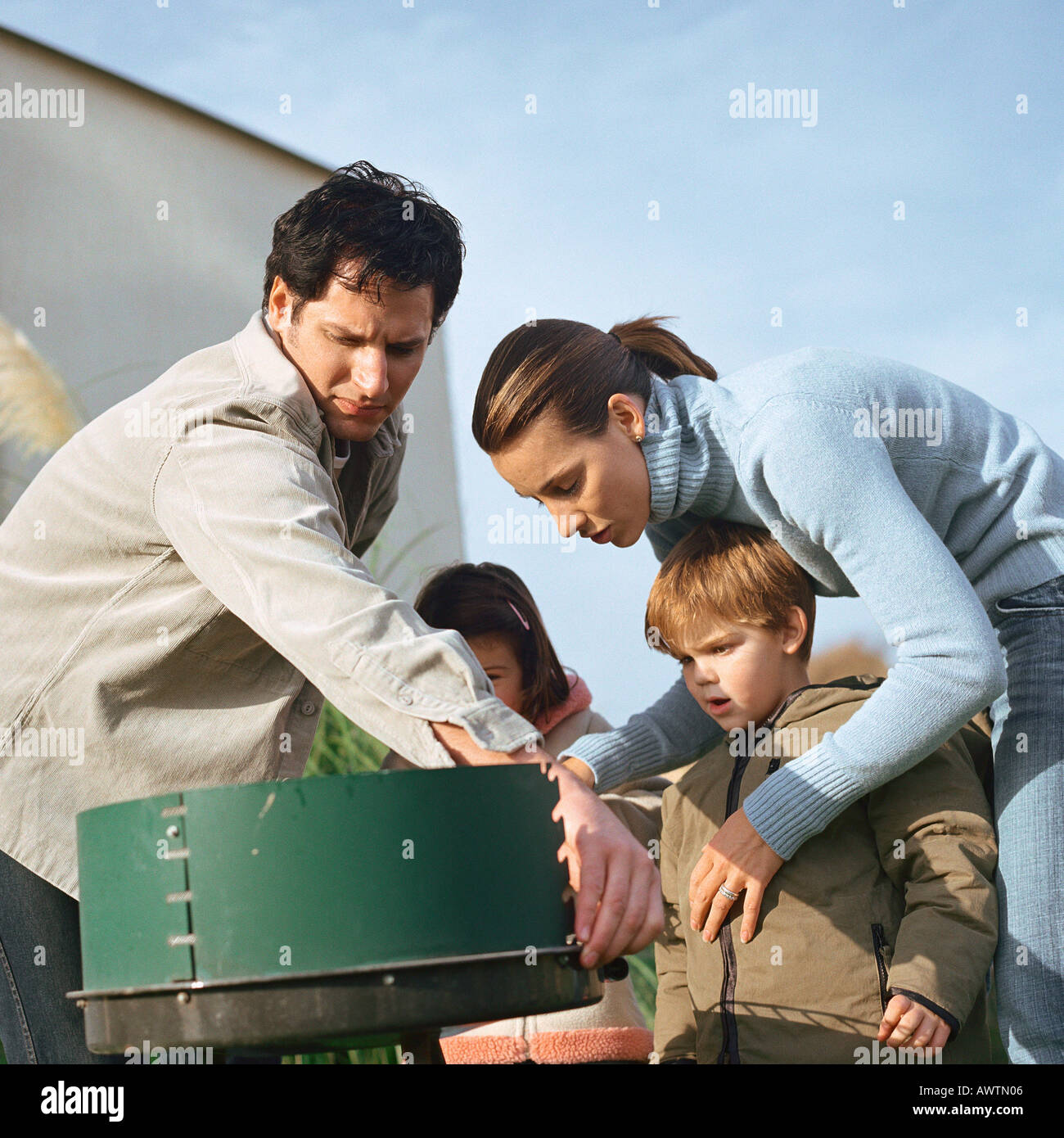 Family standing around outside grill Stock Photo