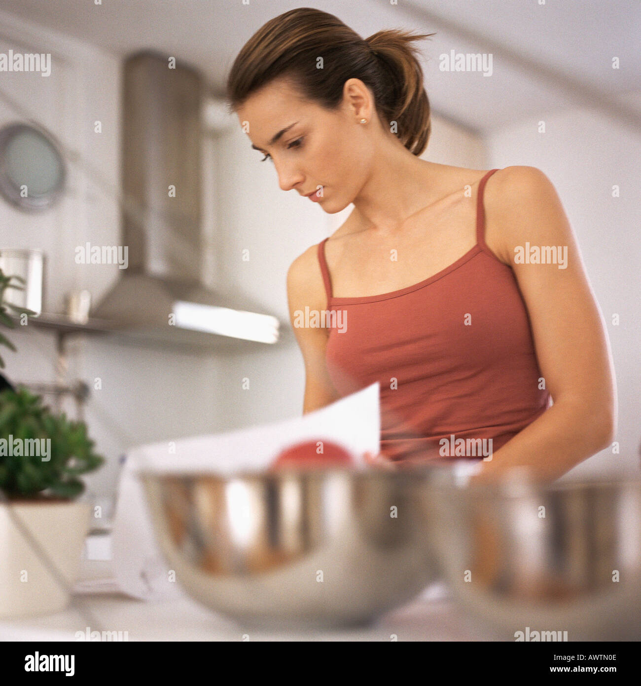 Woman working in kitchen, waist up, bowls on counter in foreground, blurred Stock Photo