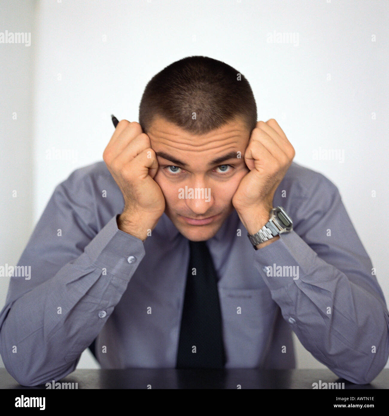 Businessman sitting with head between fists, portrait Stock Photo