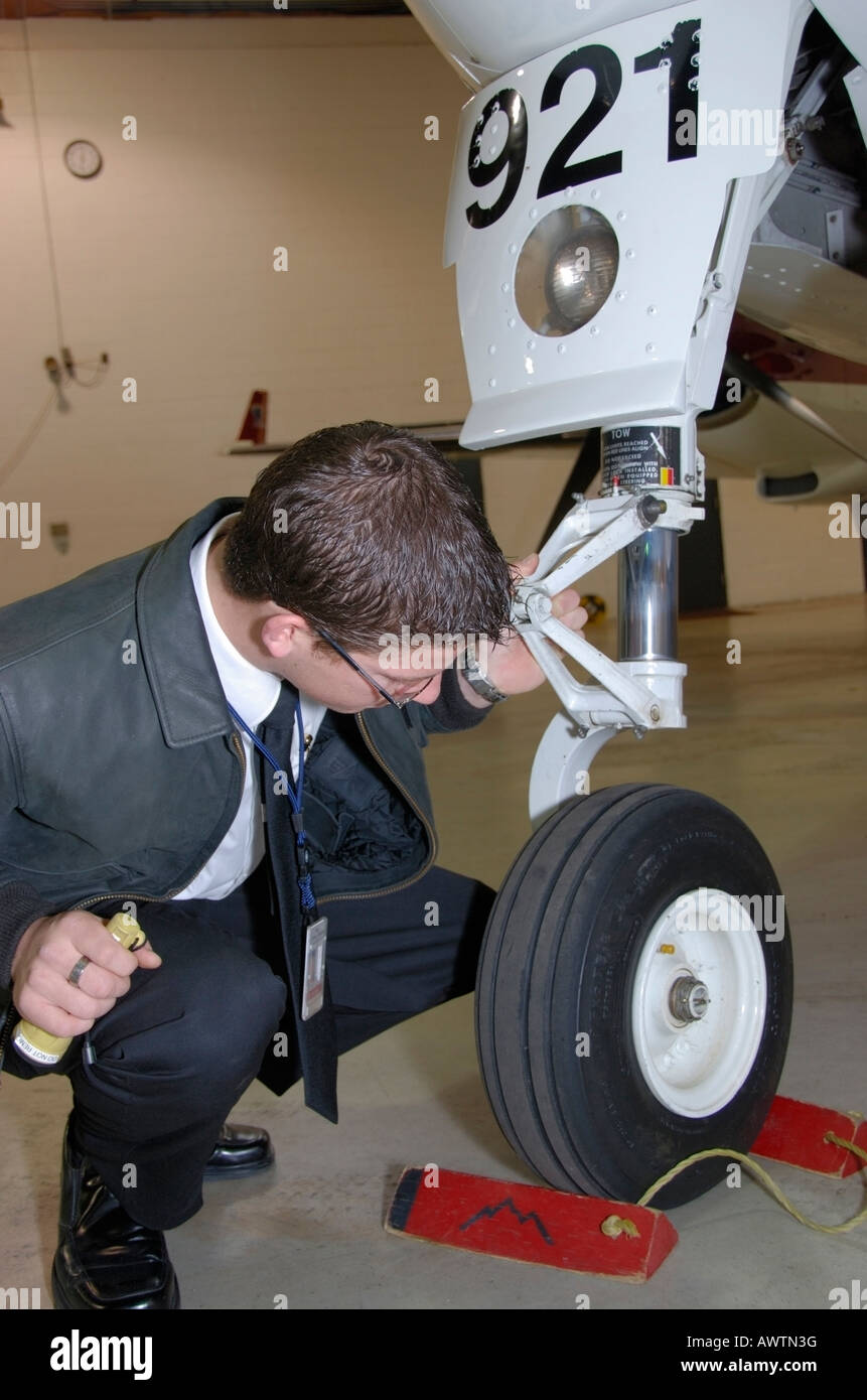 A pilot does a preflight check of the nose landing gear. Stock Photo