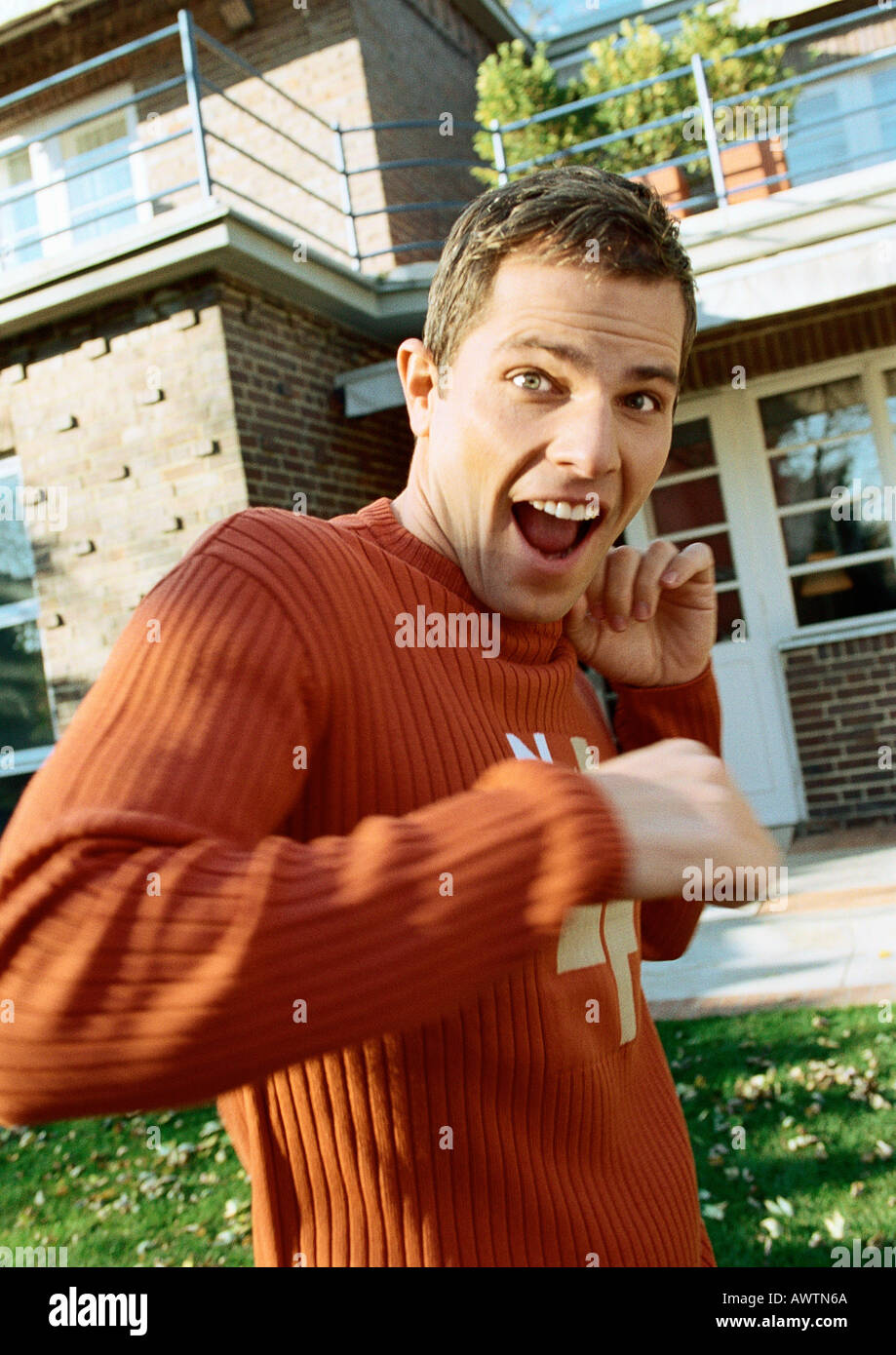 Man standing in front of house, looking surprised Stock Photo