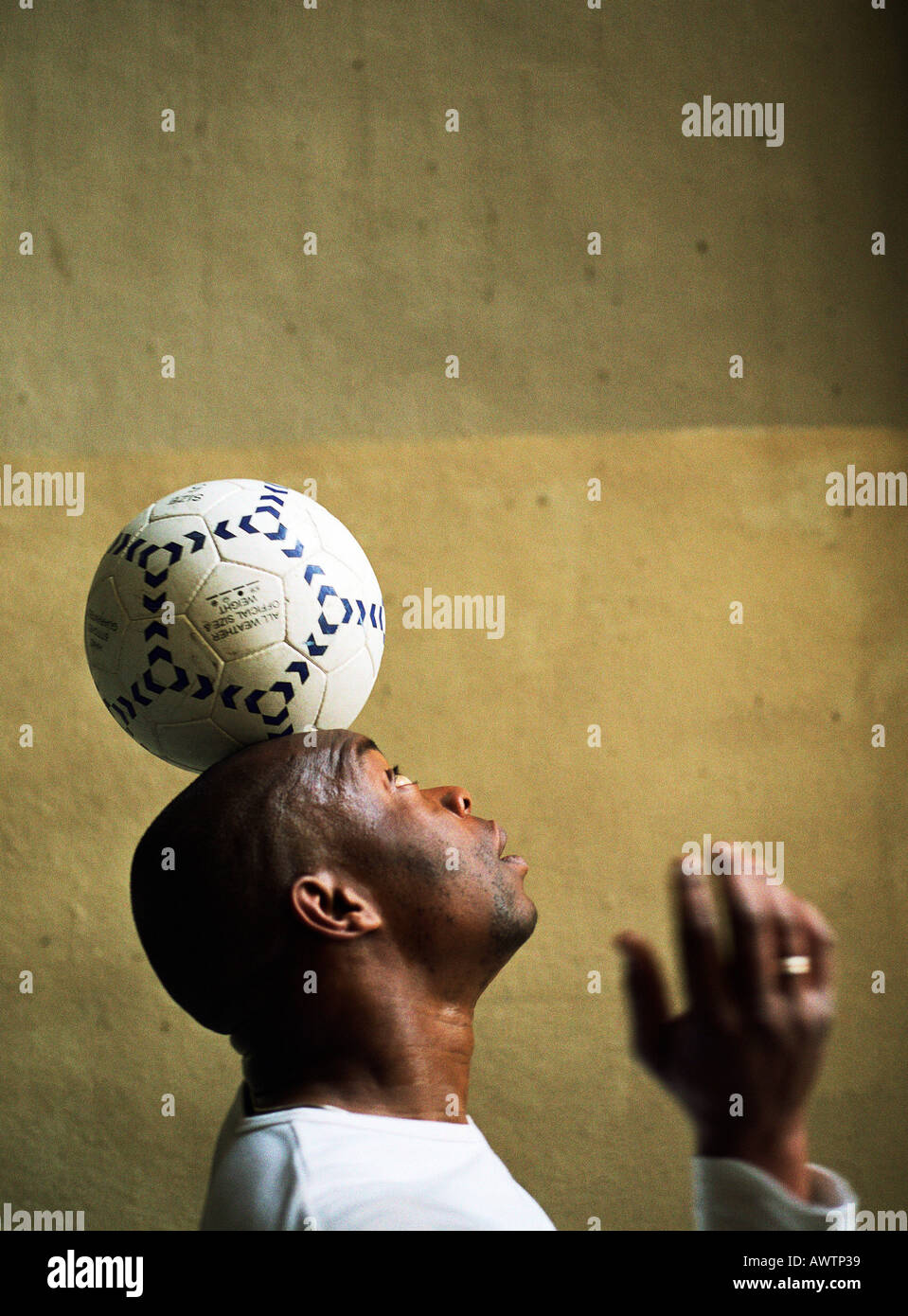 Profile view of man balancing soccer ball on head Stock Photo