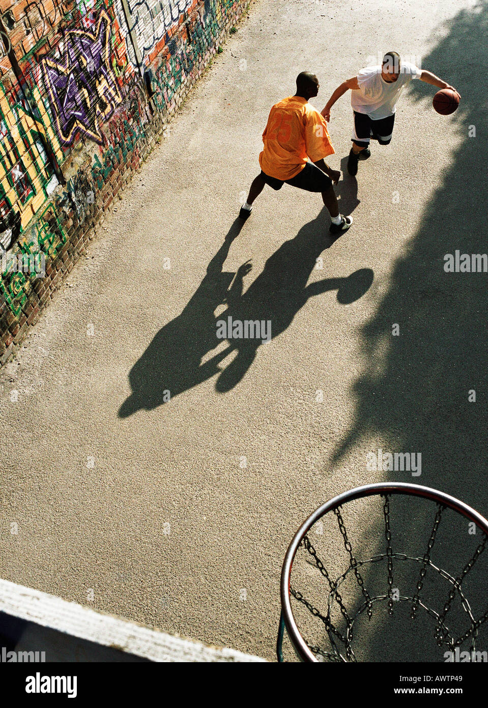 Man dribbling basketball, opponent blocking in urban playground Stock Photo