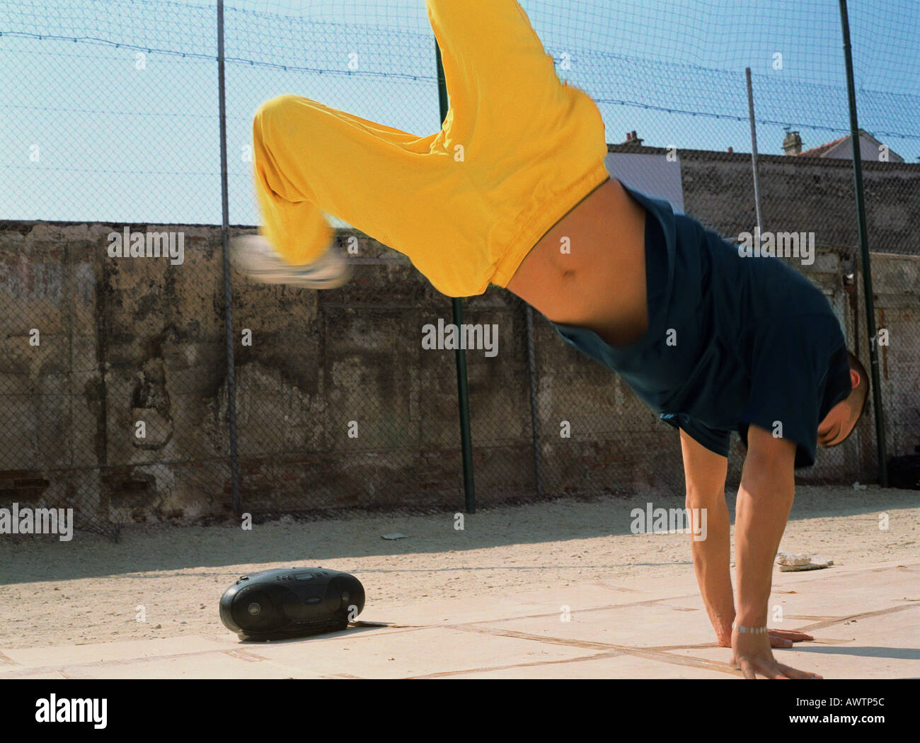 Man break dancing on hands next to radio in urban setting Stock Photo