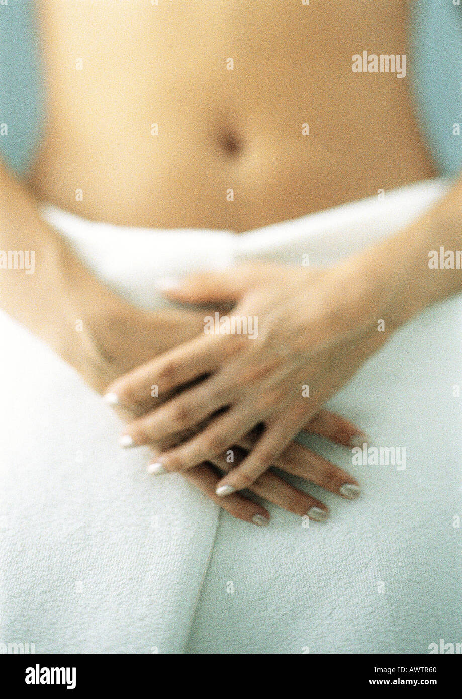 Woman with bath towel around waist, hands crossed, midsection Stock