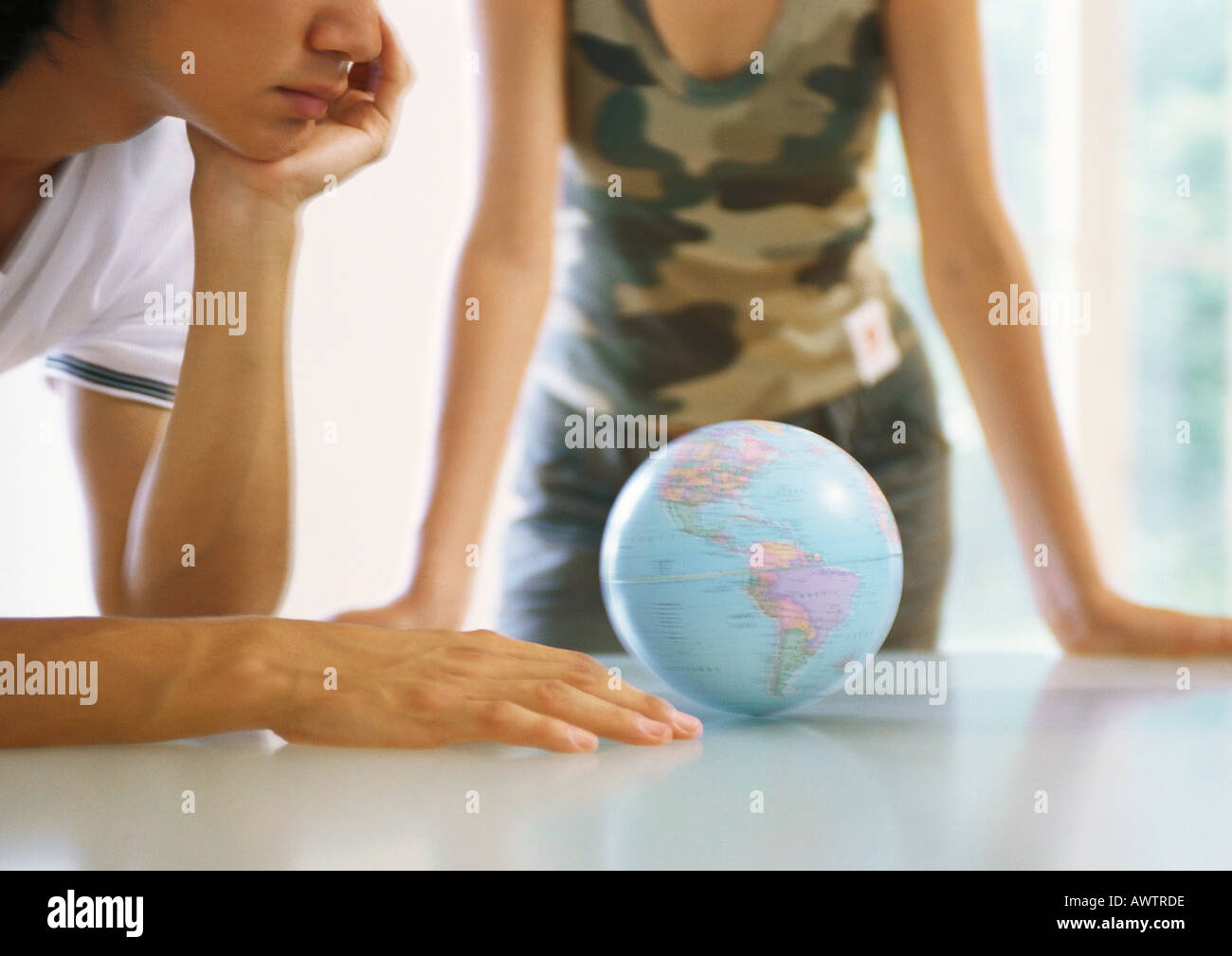 Two people looking at globe on table Stock Photo
